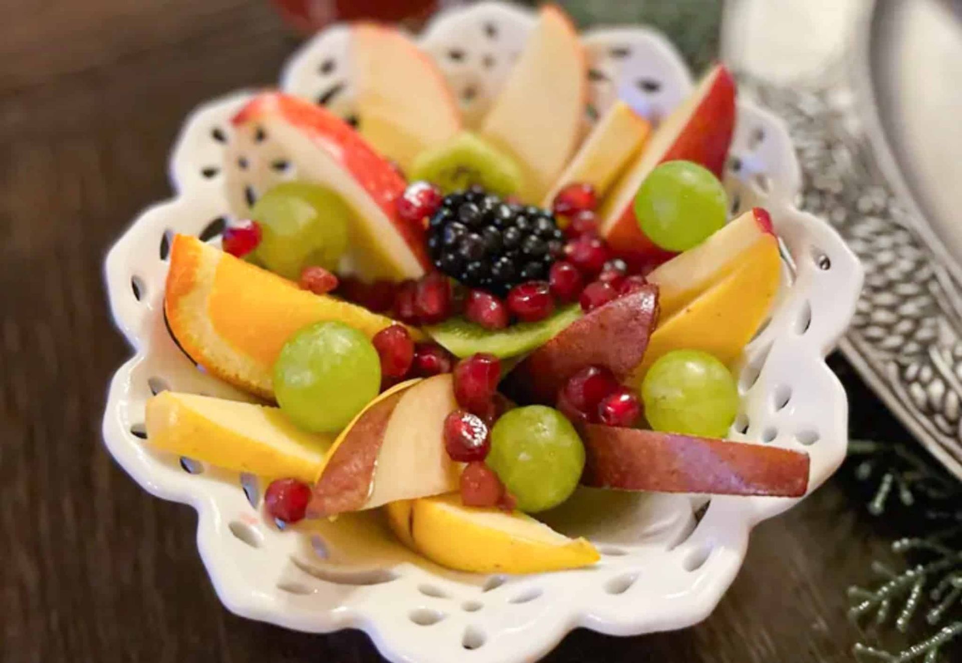 A white bowl filled with fruit and berries on a table.
