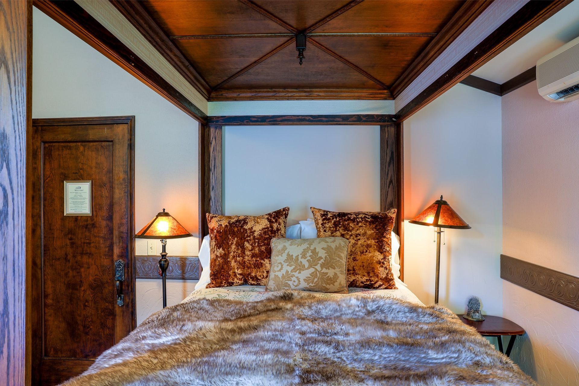 A bedroom with a four poster bed and two lamps.