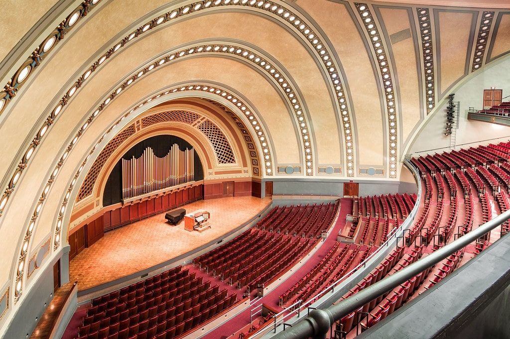 A large auditorium with red seats and an organ