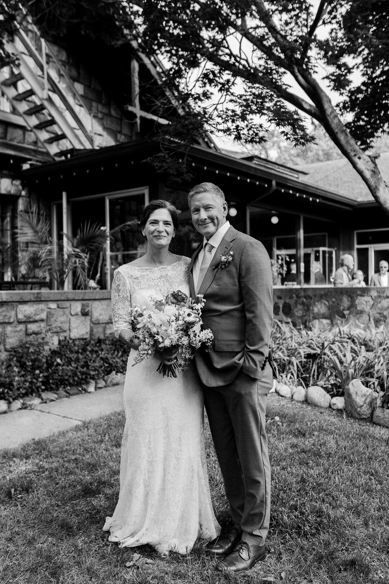 A bride and groom are posing for a black and white photo in front of a building.