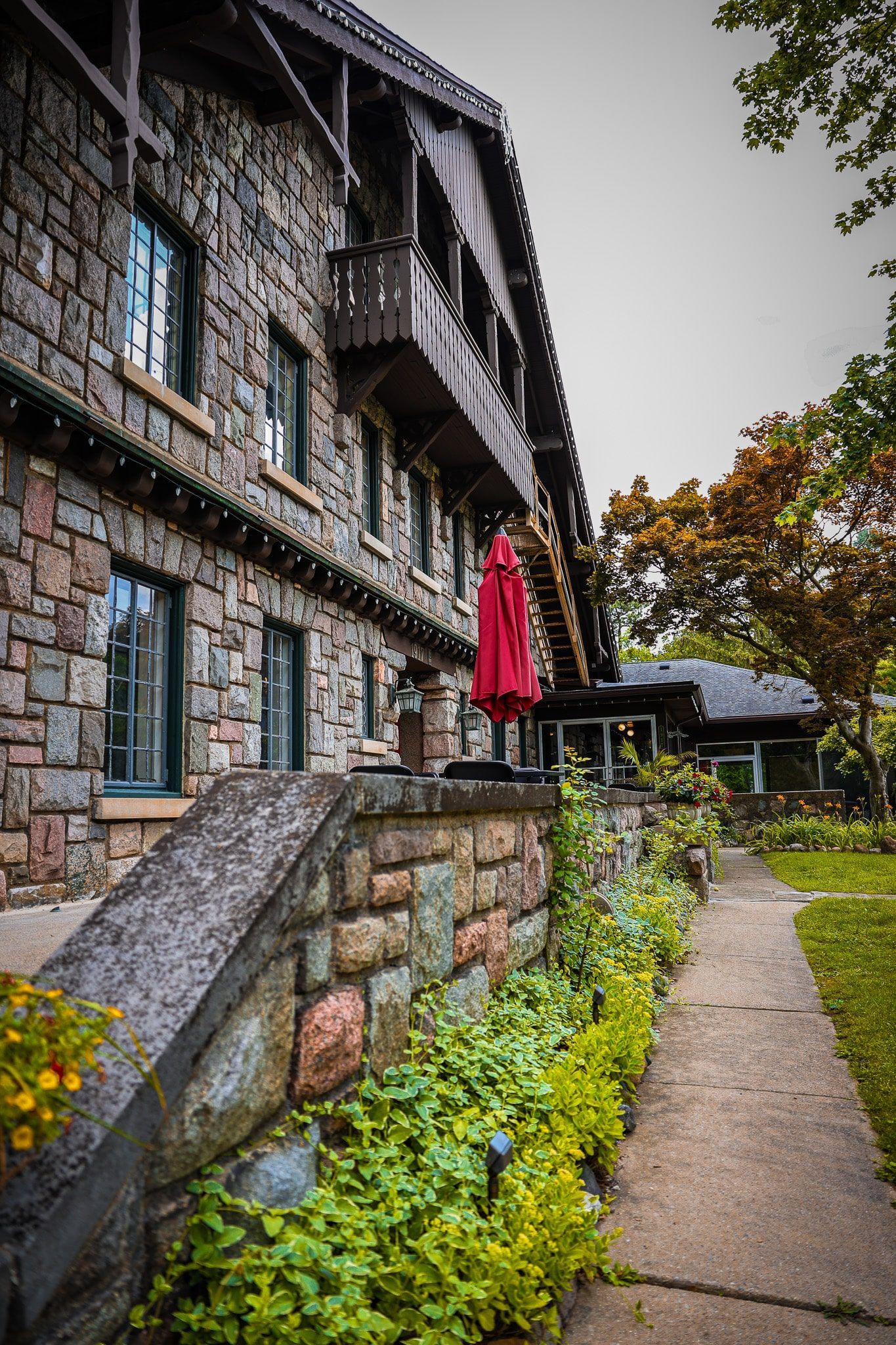 A stone building with a red umbrella in front of it.