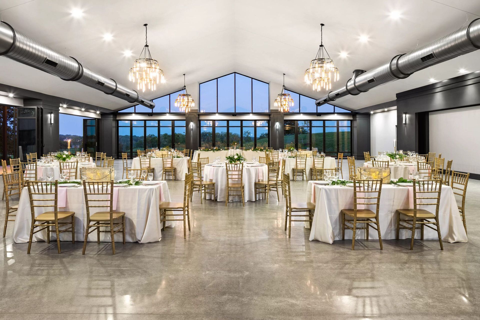 A large room with tables and chairs set up for a wedding reception.