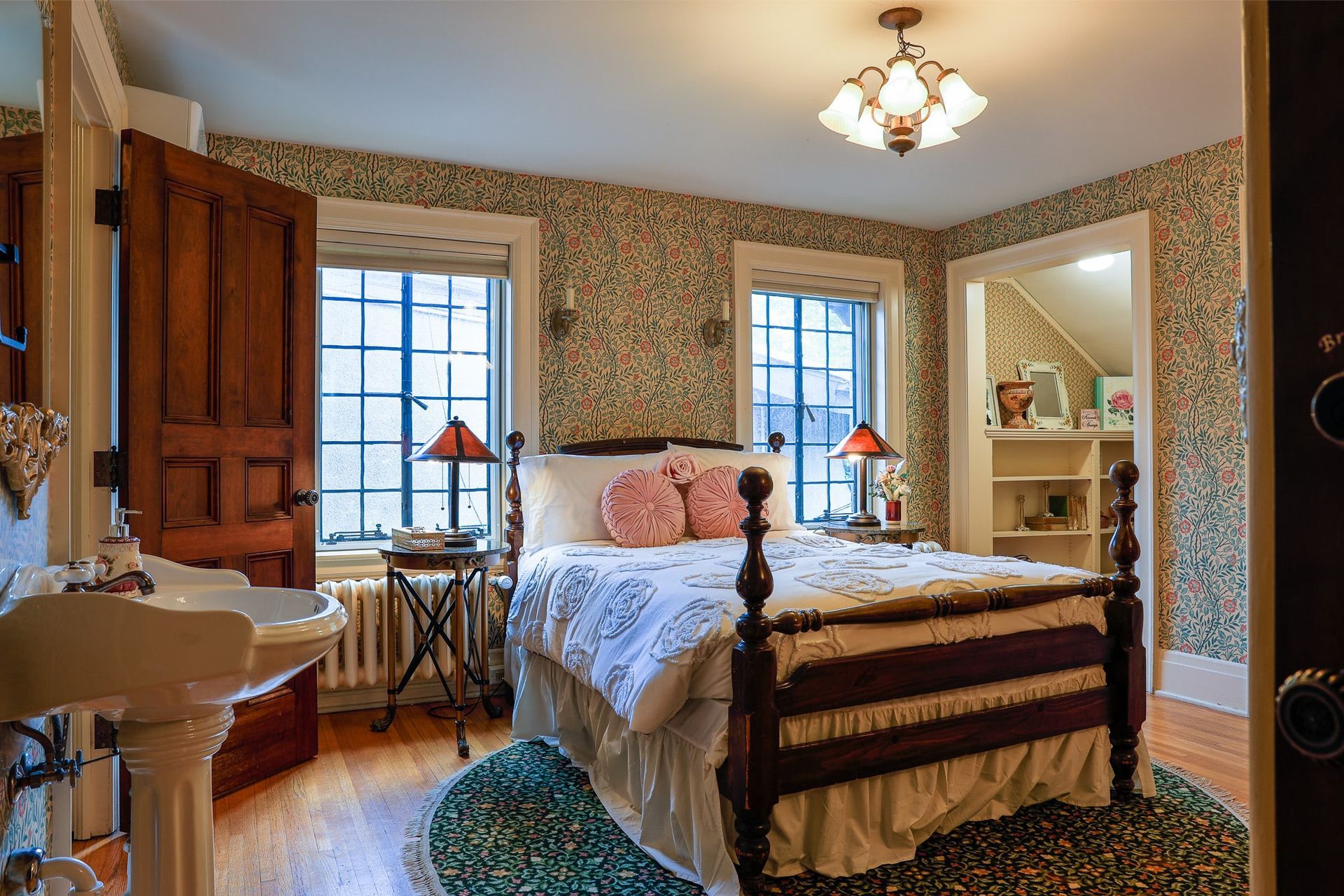 A bedroom with a bed , sink , and window.