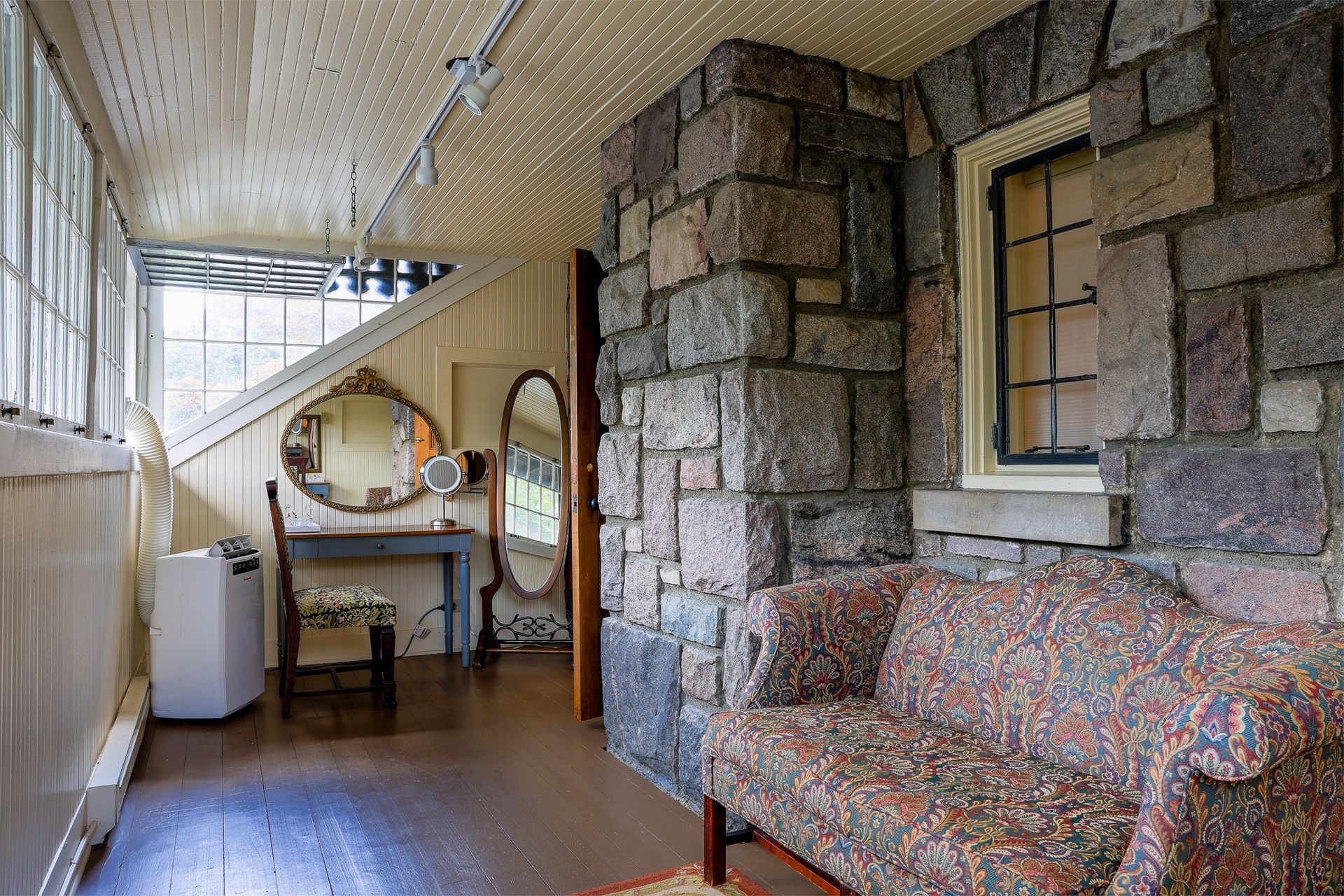 A living room with a couch , chair , table and mirror.