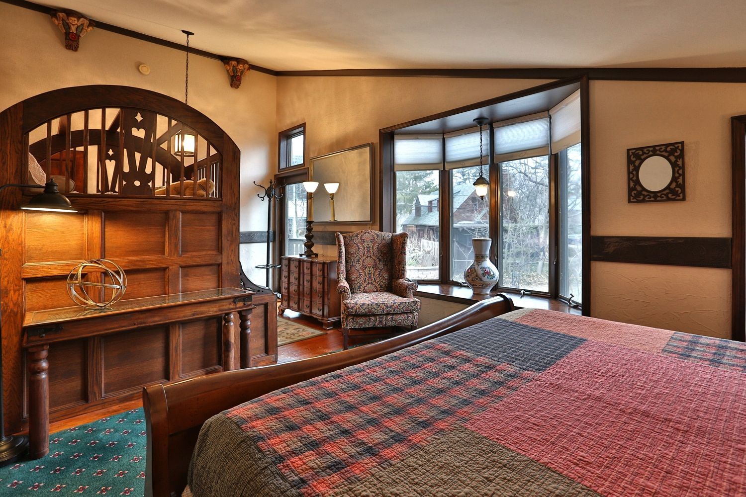 A bedroom with a large bed , chair , table and windows.