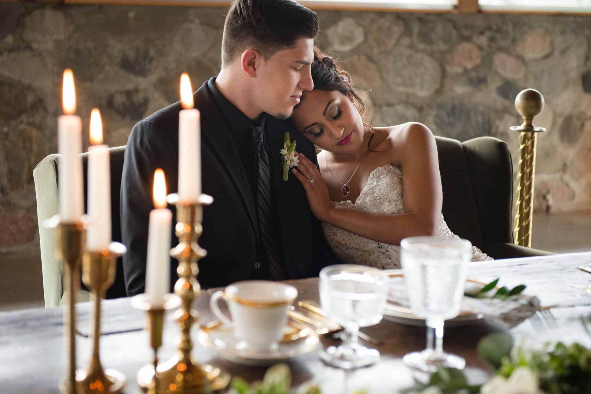 A bride and groom are sitting at a table with candles.