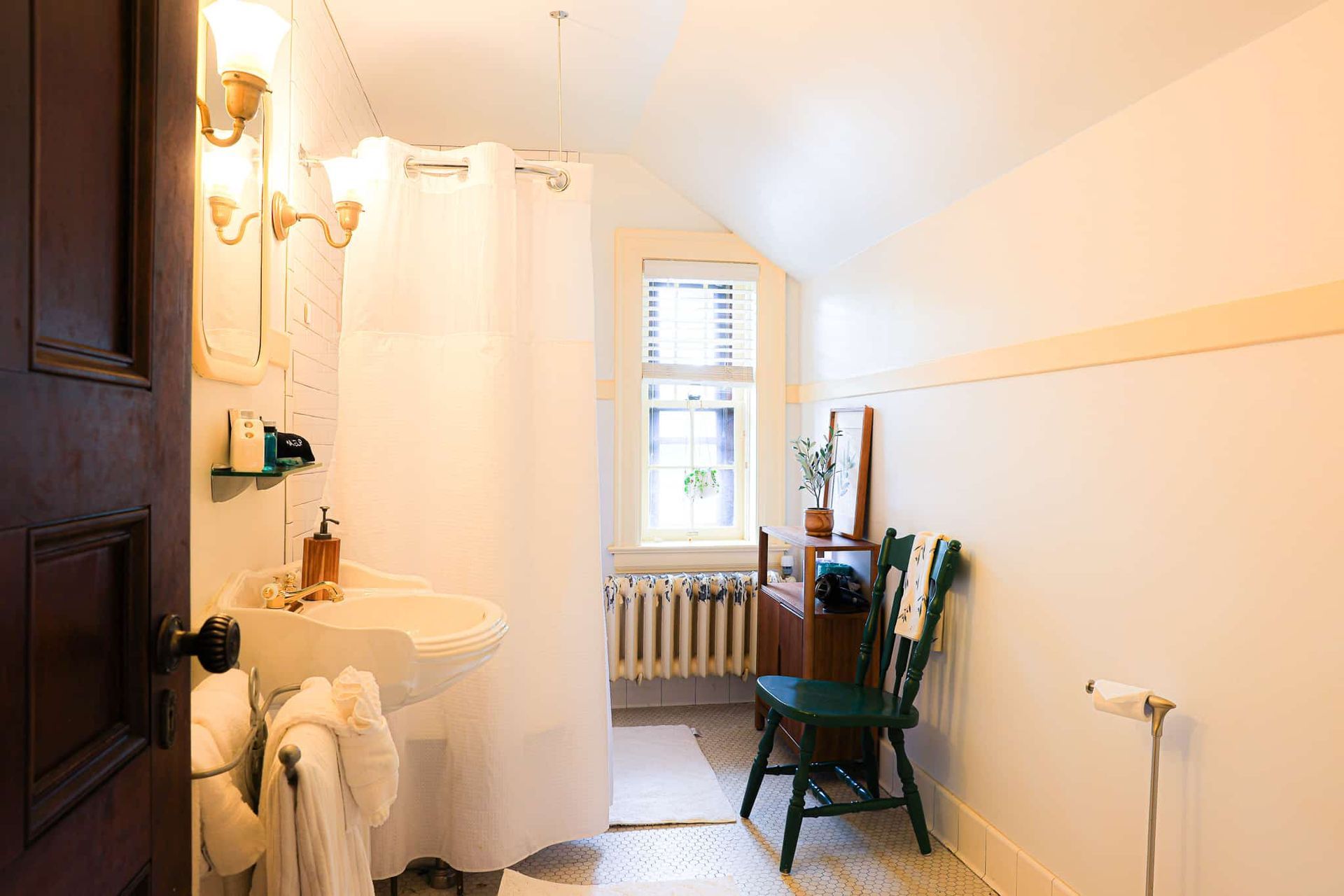 A bathroom with a sink , chair , and shower curtain.