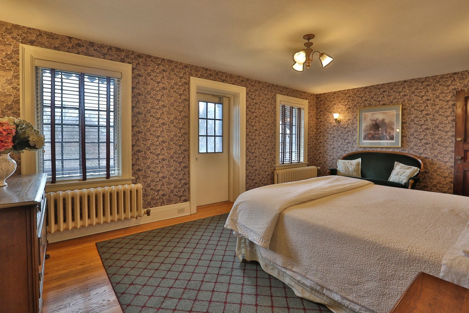 A bedroom with a king size bed , dresser , chair and window.