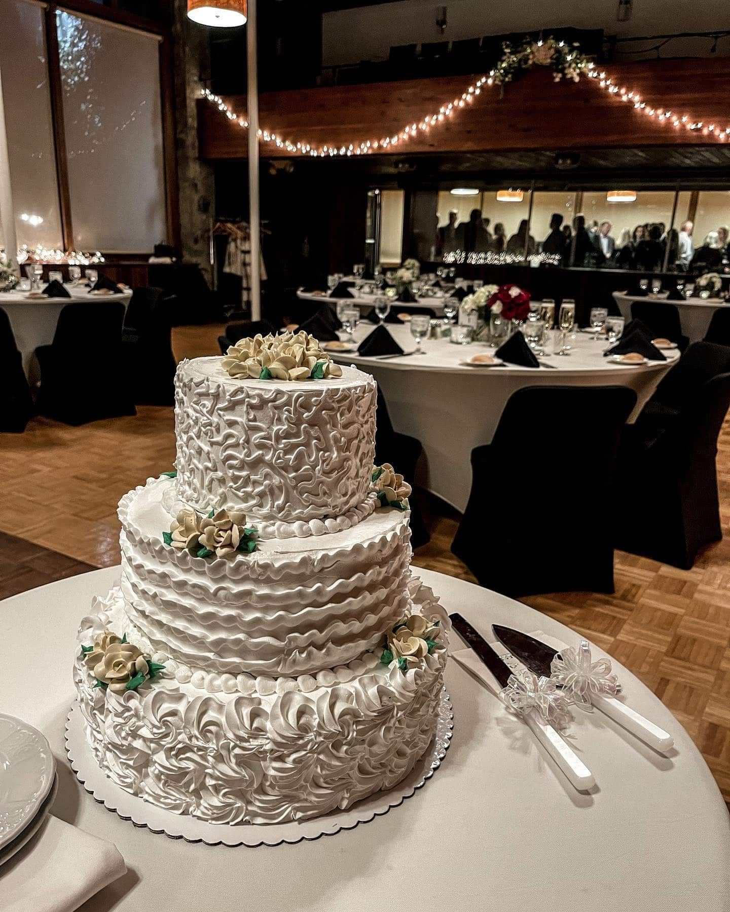 A wedding cake is sitting on a table with knives and forks.