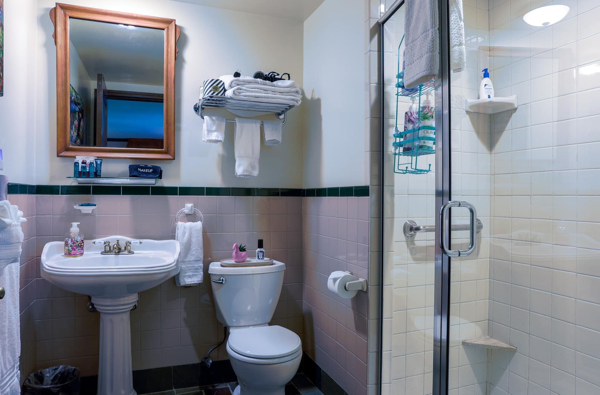 A bathroom with a toilet , sink , mirror and shower.