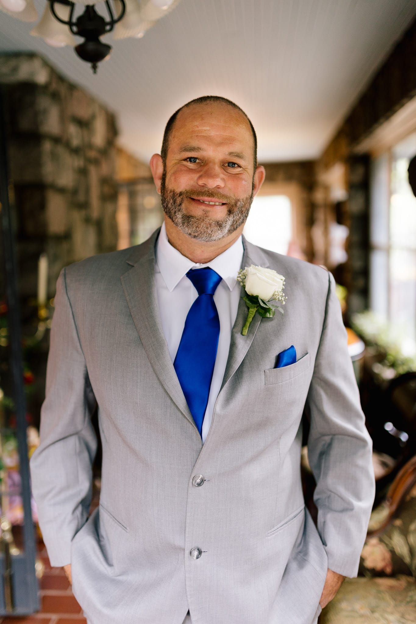 A man in a suit and blue tie is standing with his hands in his pockets.