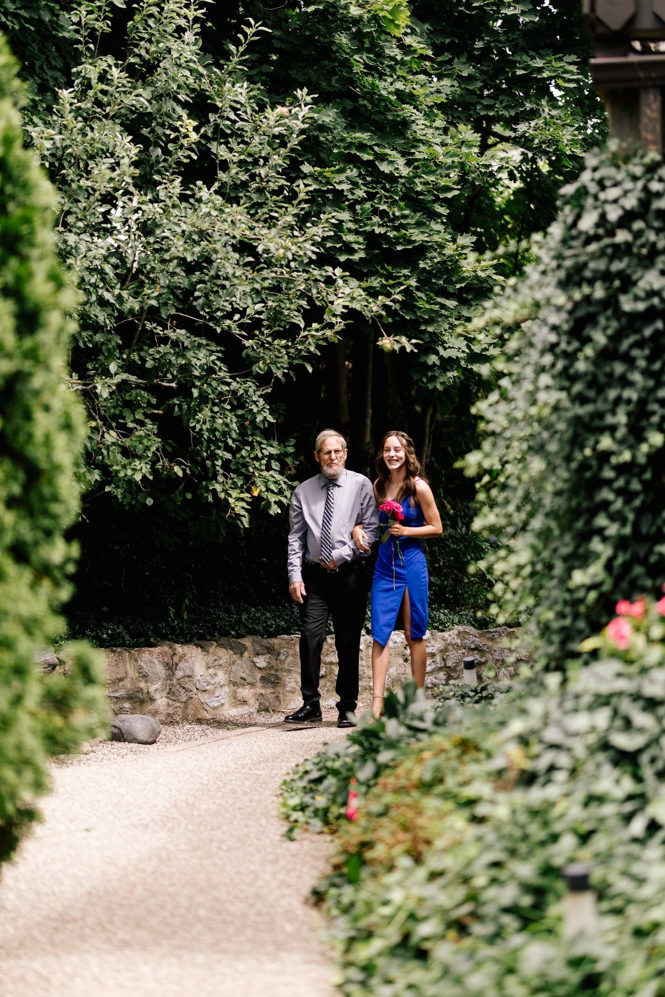 A man and a woman are walking down a path in the woods.