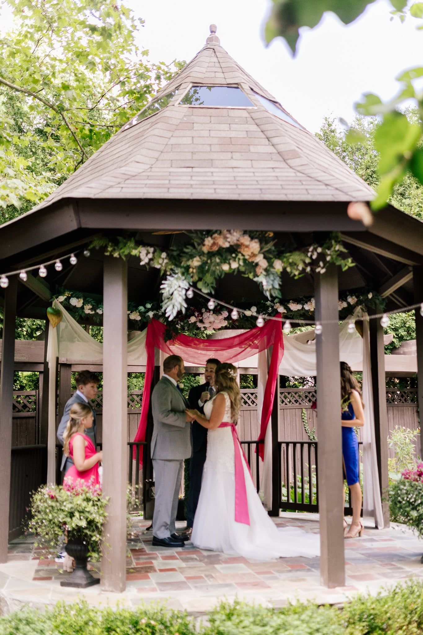 A bride and groom are getting married in a gazebo.