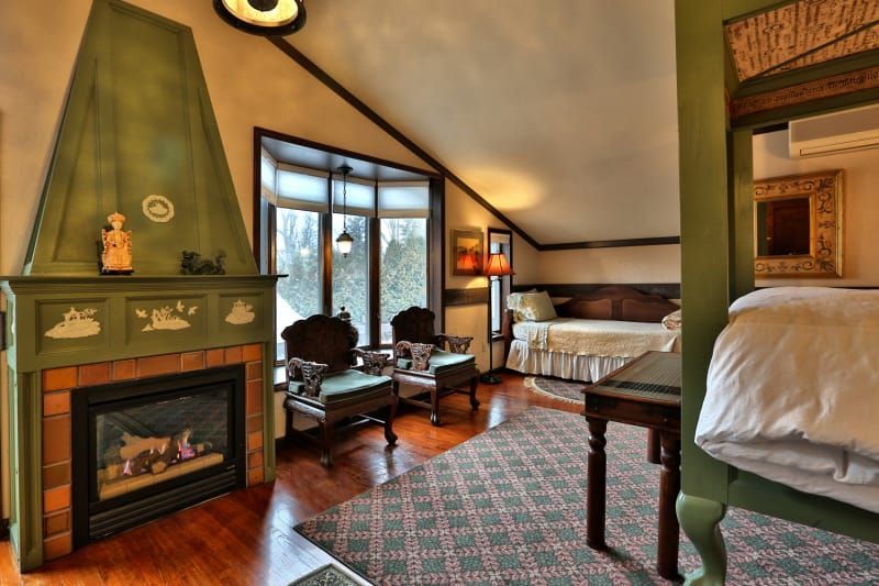 A bedroom with a green fireplace and a bed