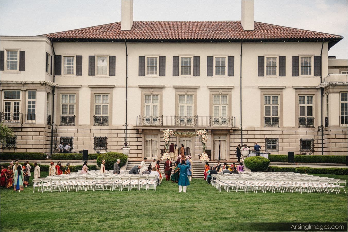 A group of people are standing in front of a large white building.