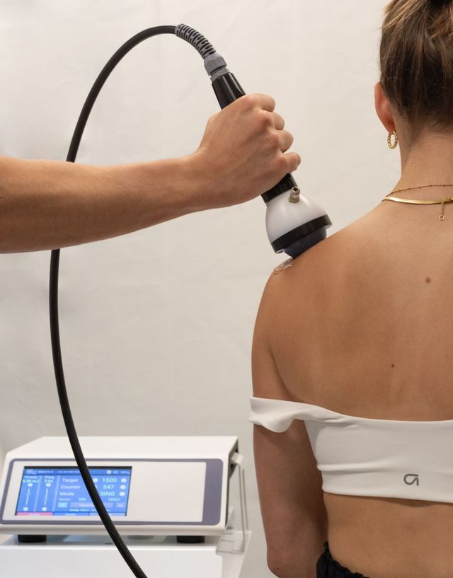 Clinic worker using a handheld device on a patient's bare back during a treatment session