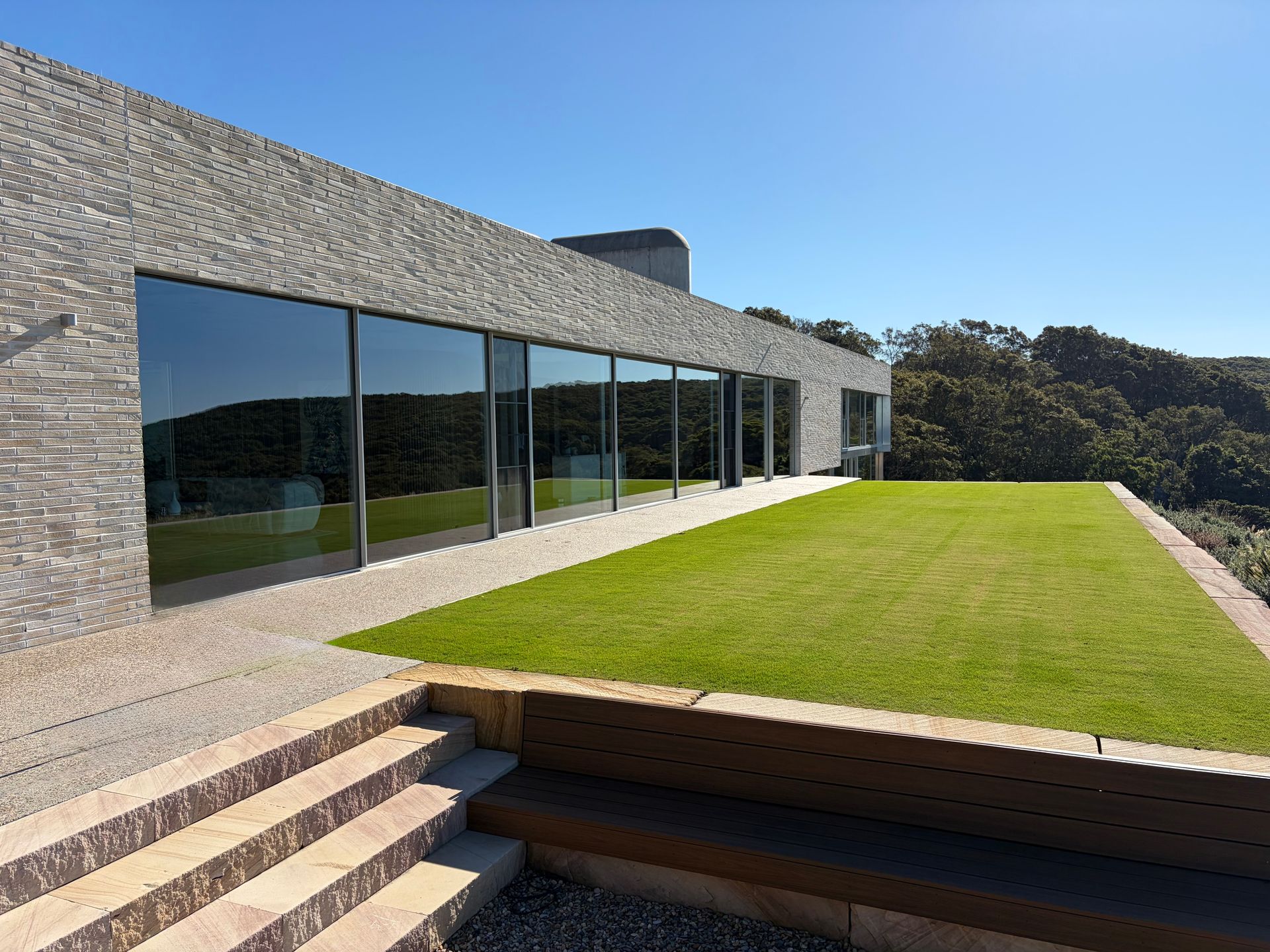 Window Squeegee Cleaning a Glass Door with Patio and Distant City View Behind It — Eastons Window Cleaning in Cardiff, NSW