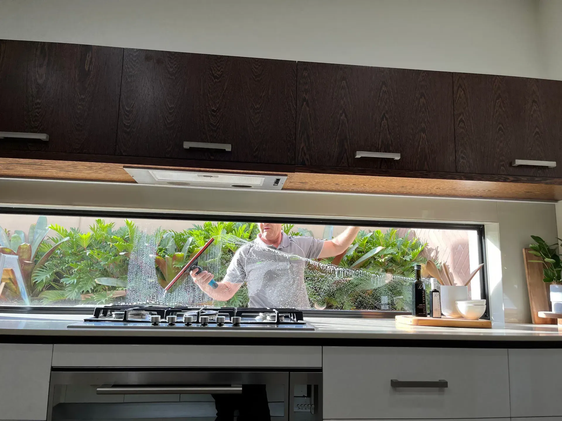 Person Visible Through Kitchen Window, Reaching Toward the Sink from Outside — Eastons Window Cleaning in Cardiff, NSW