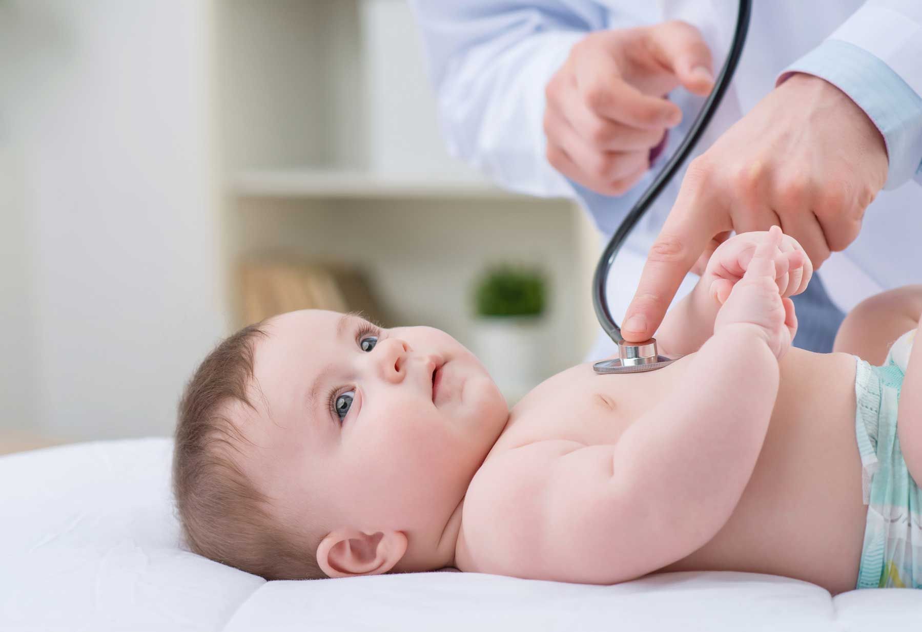 A baby is being examined by a doctor with a stethoscope.