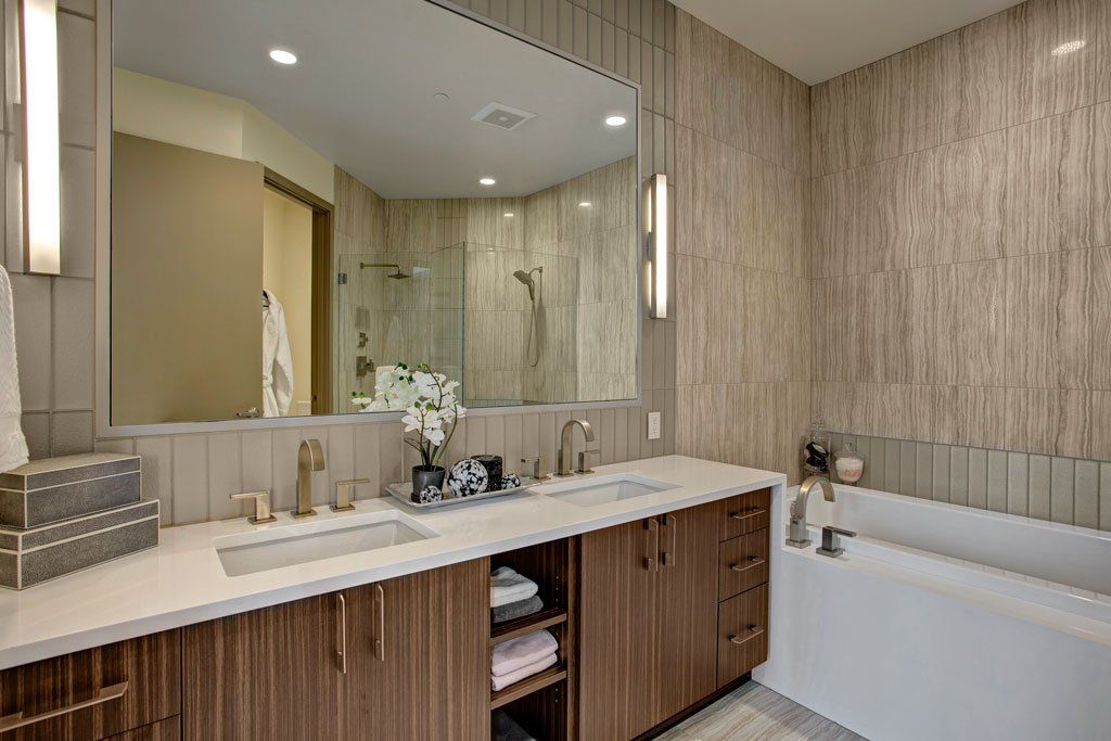 A bathroom with two sinks, a tub, and a large mirror at Tower12 Apartments.