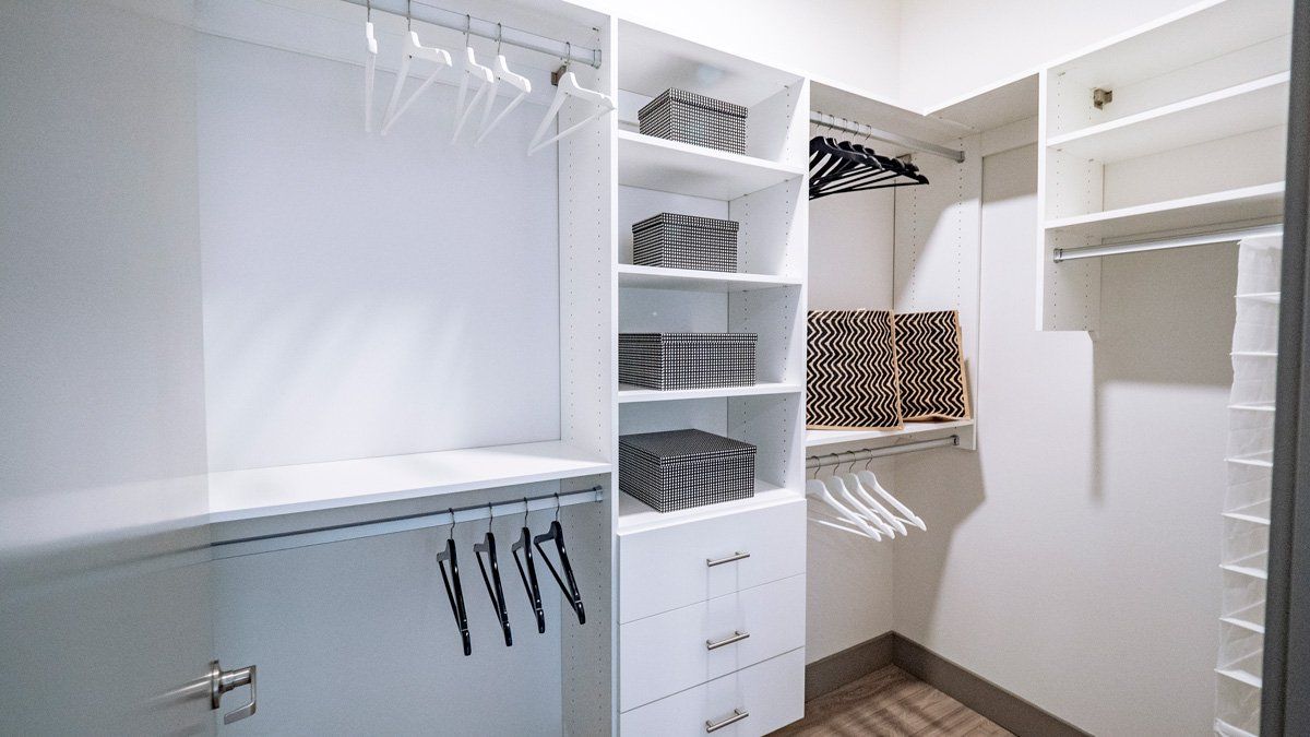 A walk in closet with a lot of shelves and clothes hanging on the racks at Tower12 Apartments.