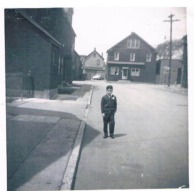 Child standing in the middle of a quiet street with houses and utility poles in the background