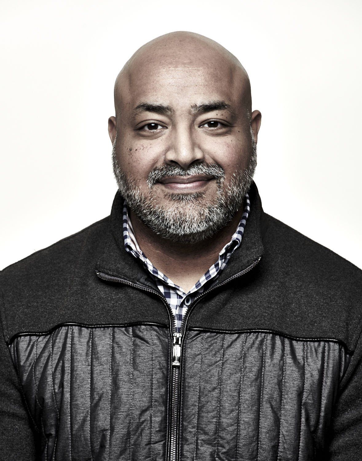 Portrait of a smiling man in a dark jacket against a light background