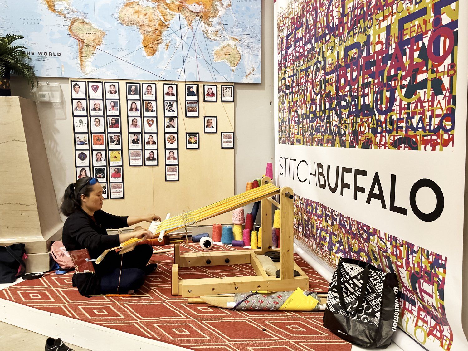 Person seated on a rug in a colorful classroom with art displays, maps, and a “BUFFALO” banner