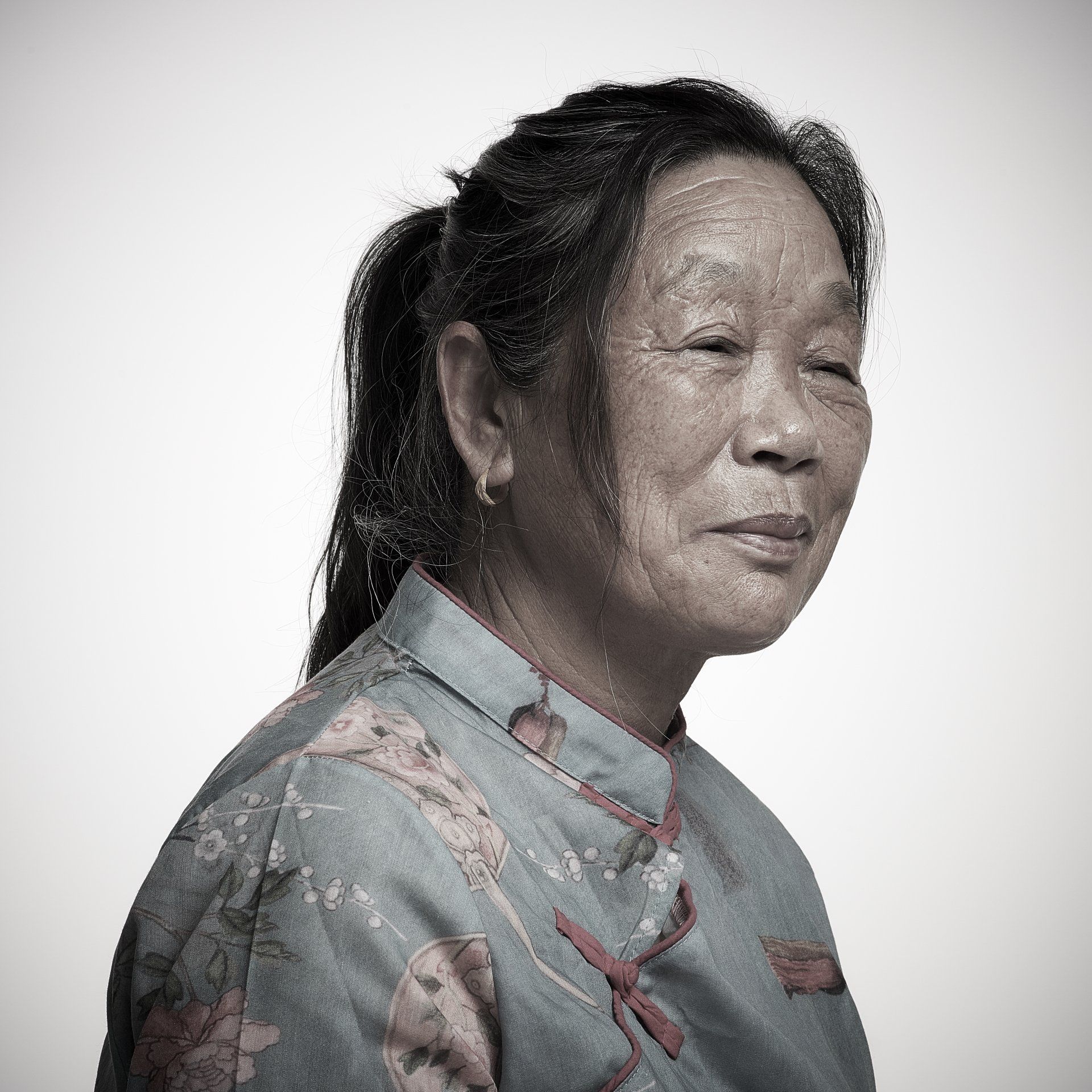 Portrait of a woman in a floral blouse, facing right against a plain white background