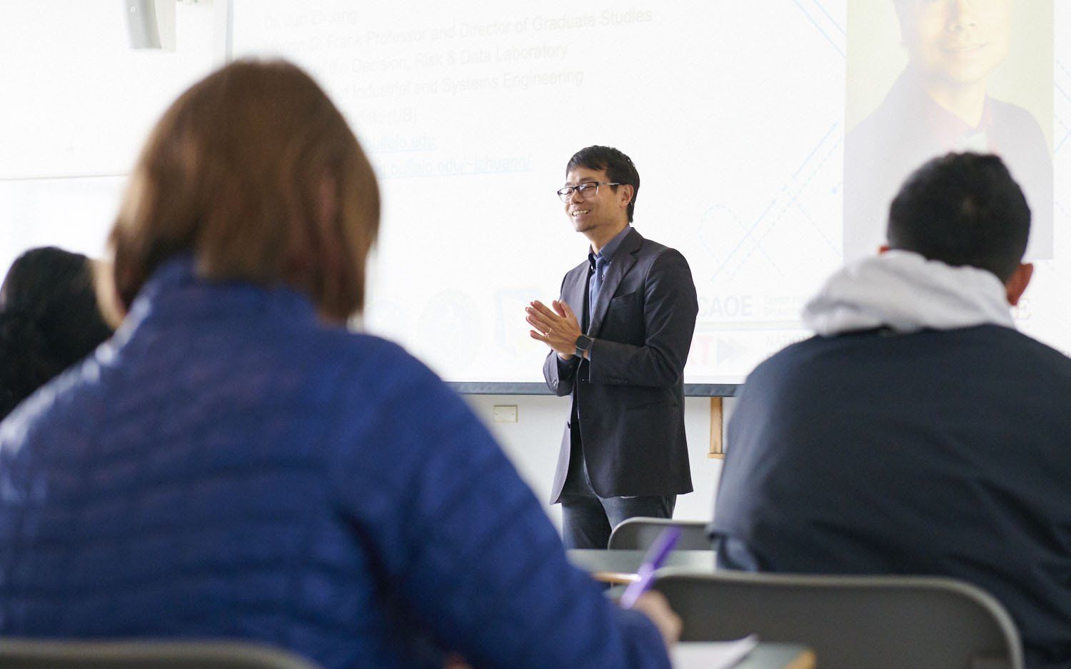 Presenter speaking to an audience in a bright classroom or lecture hall