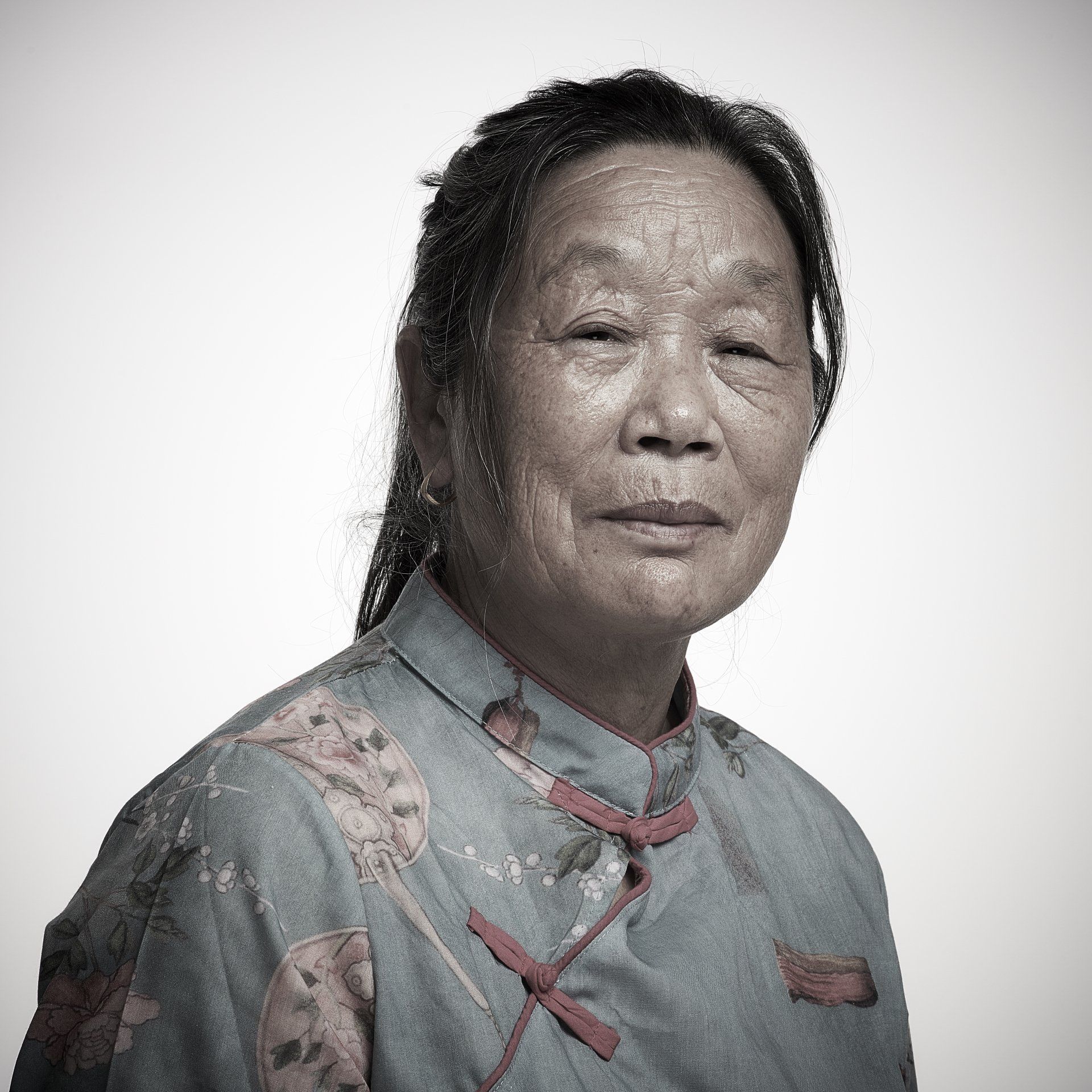 Portrait of a person in a gray floral top, facing the camera against a light background