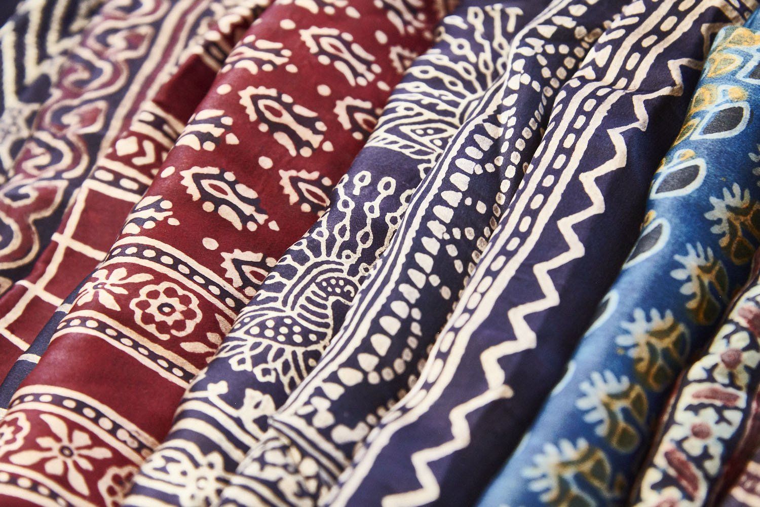 Patterned folded fabrics in red, blue, and white with intricate floral and geometric designs