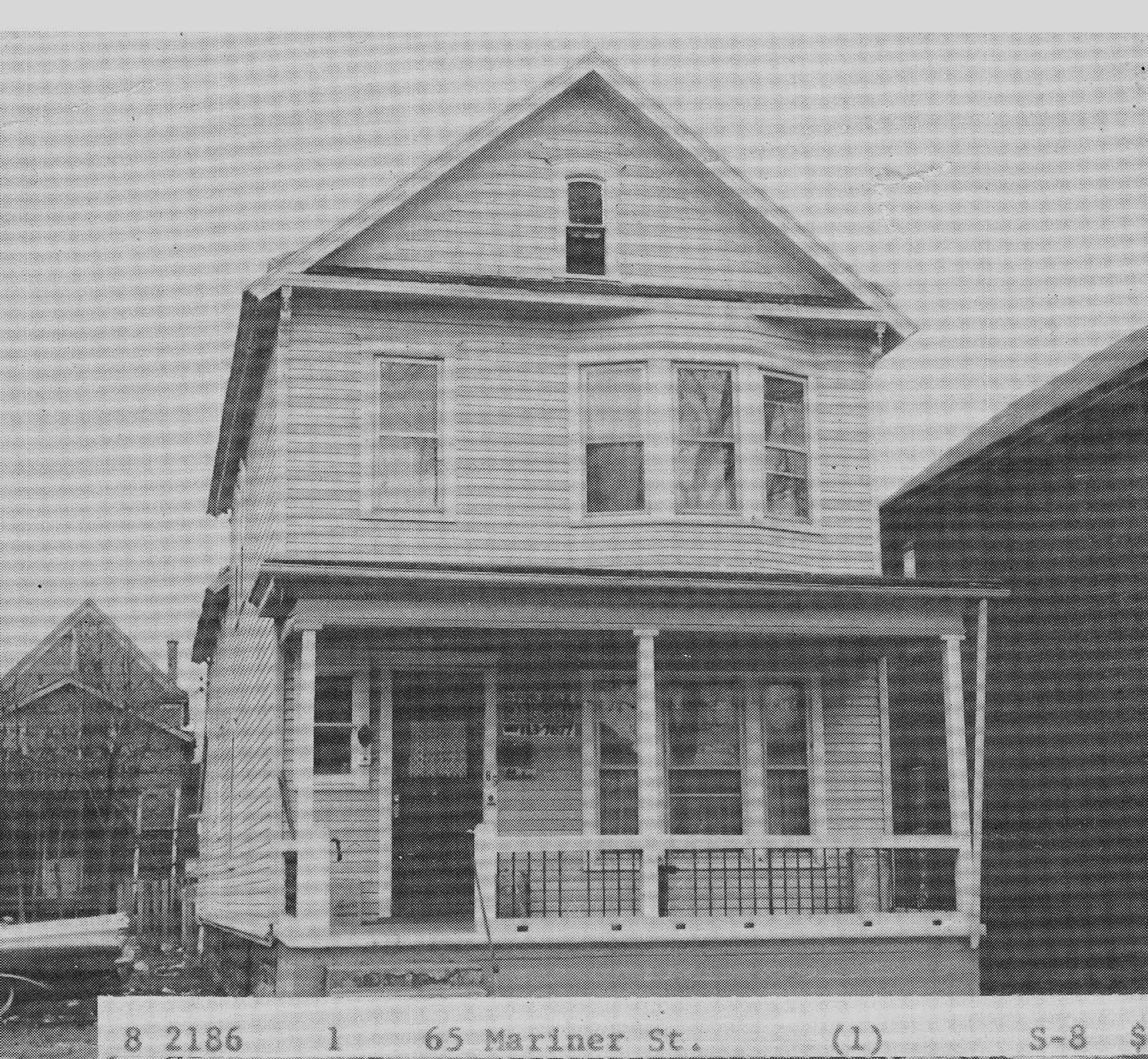 White two-story house with a front porch and gabled roof, seen from the street