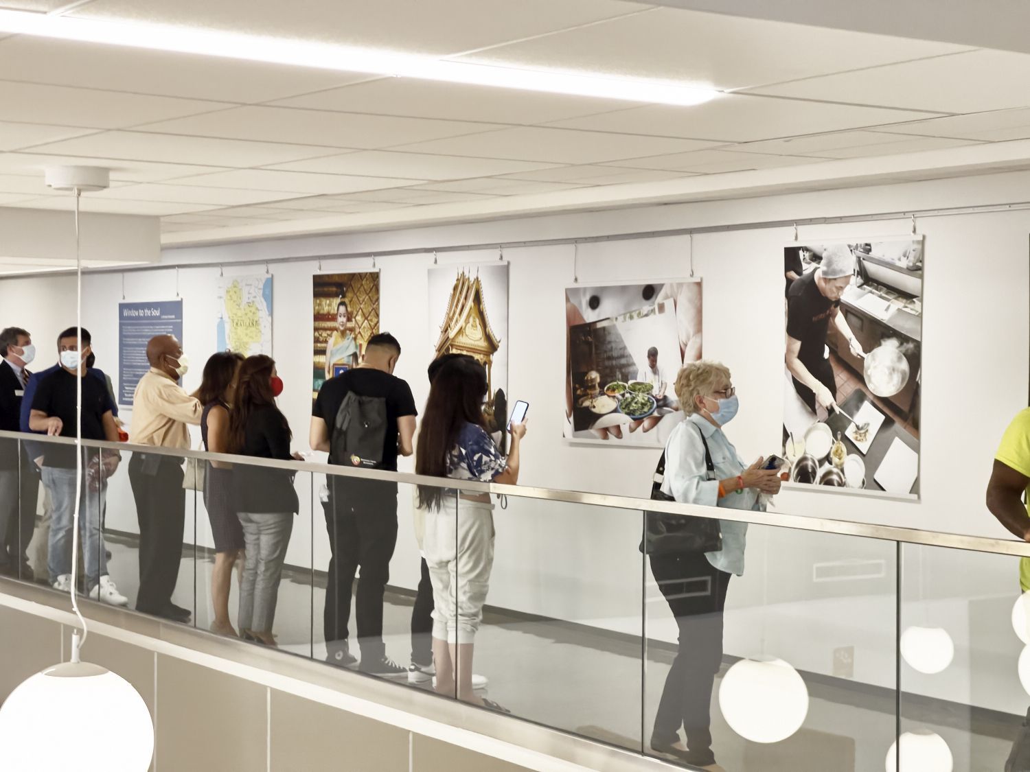 People viewing art in a bright gallery corridor beside large black-and-white photographs