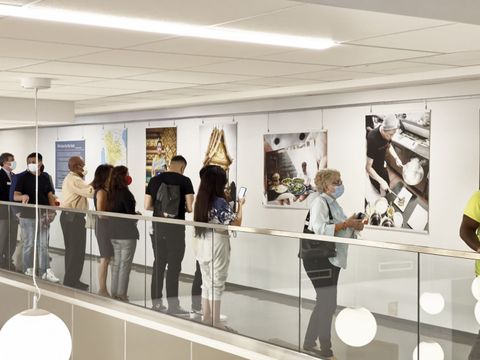 People viewing art in a bright gallery corridor beside large black-and-white photographs