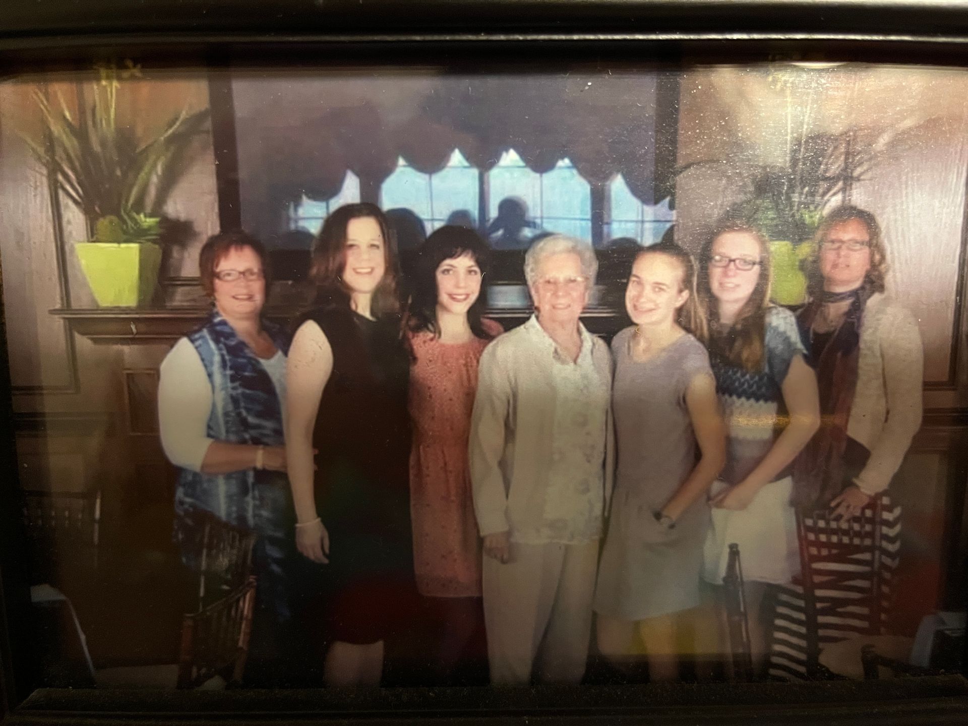 Six people posing indoors in front of a window, dressed in formal attire.
