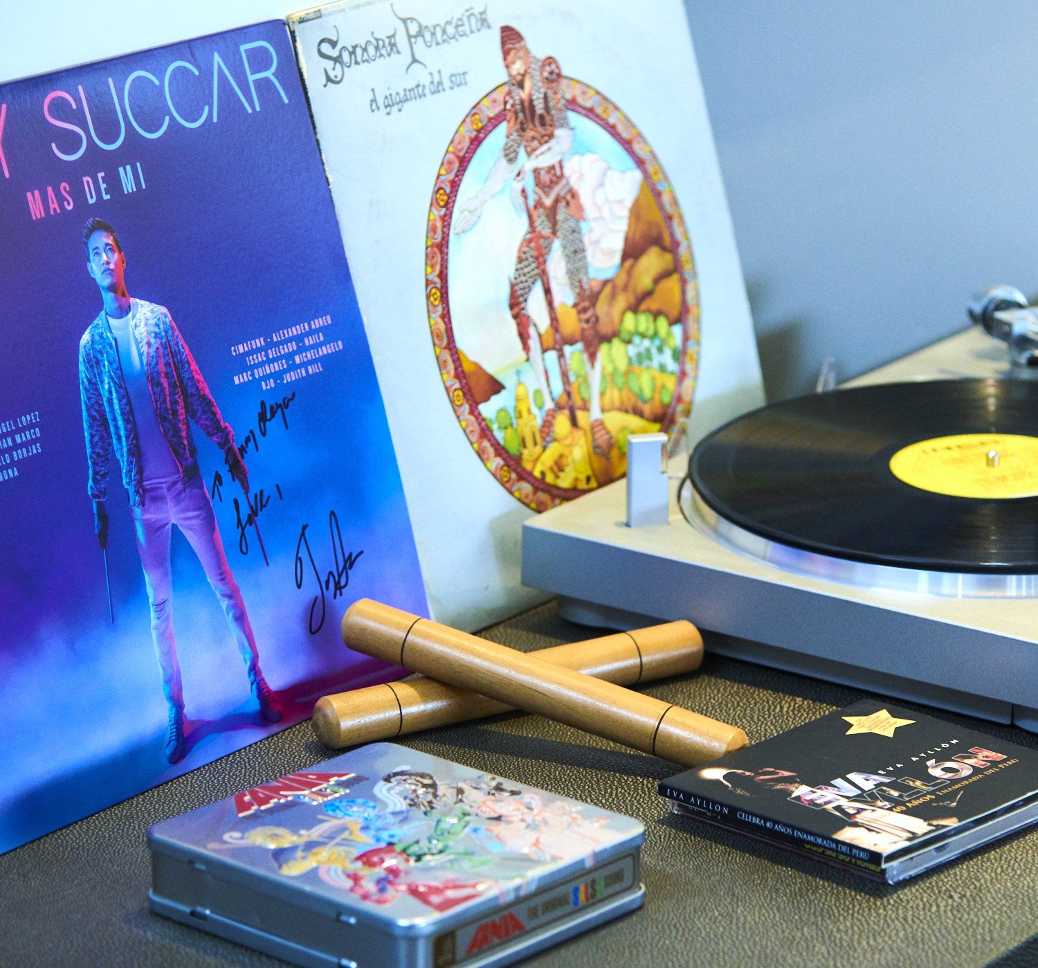 Vinyl records and album covers displayed beside a record player on a table.