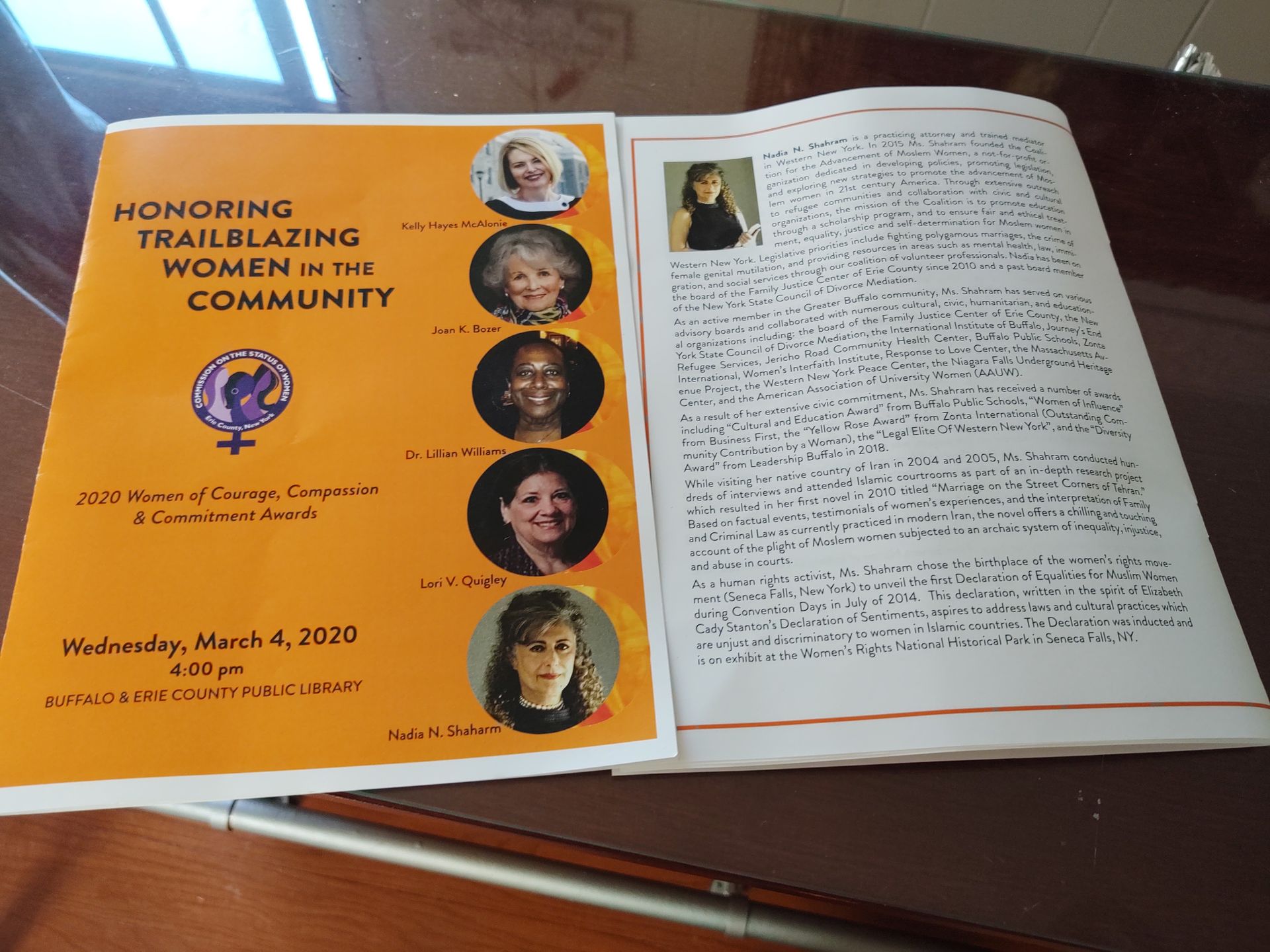 Open booklet on a table: orange seminar cover beside a page of dense text and a small portrait.