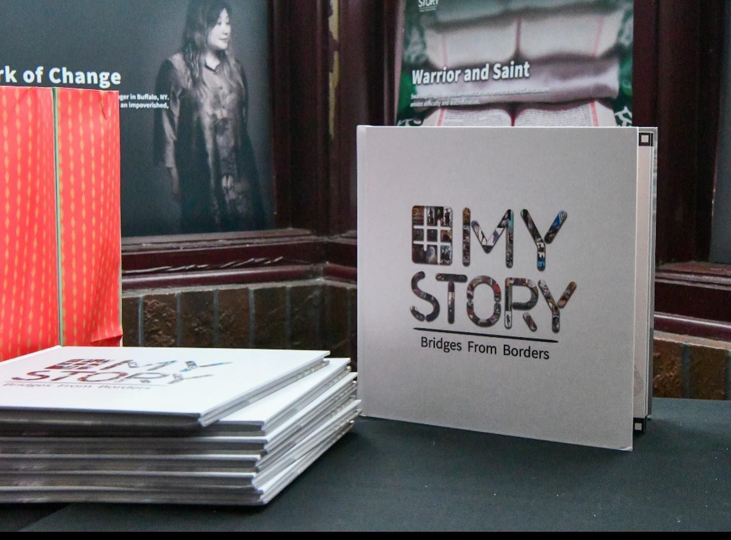Stack of books beside a white book titled “My Story” on a dark tabletop.