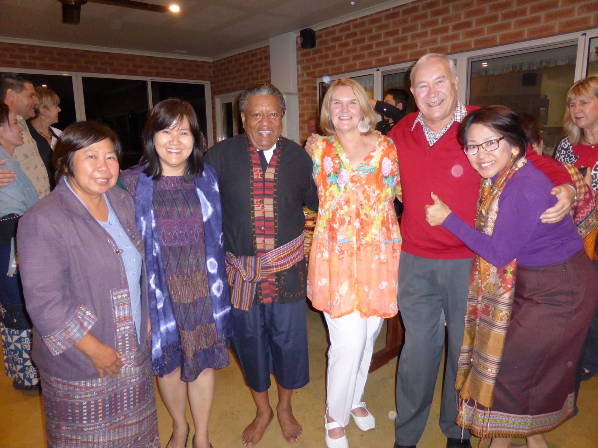 Group of six people posing indoors at a festive gathering, smiling and wearing colorful outfits.