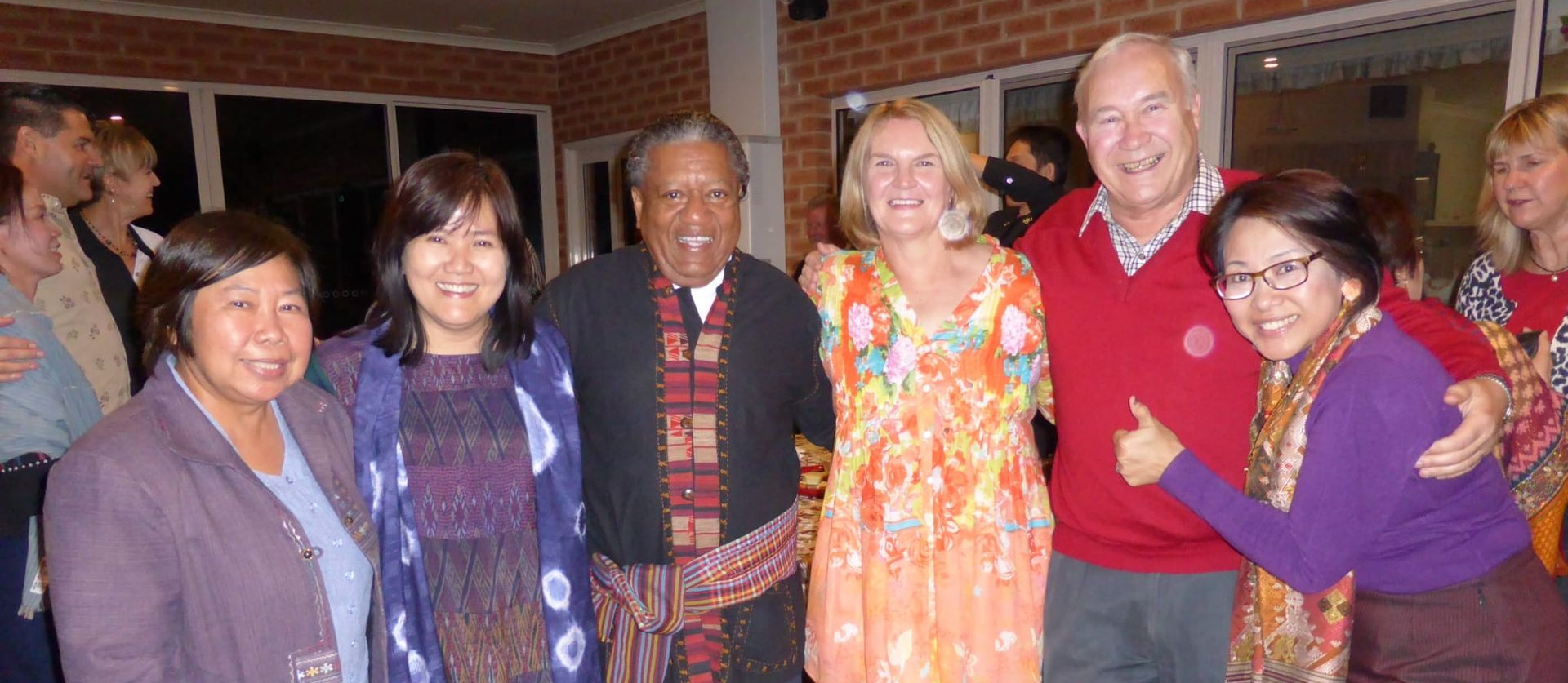 Group of people smiling and posing together indoors, with one person making a peace sign.