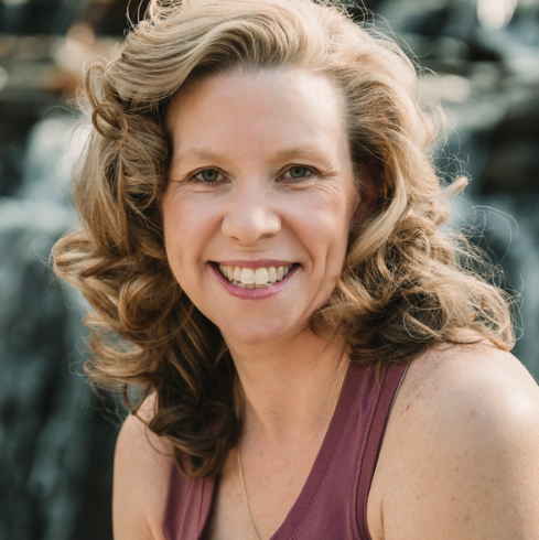 Andrea Pfannstiel, 500-hour certified yoga instructor, smiling outdoors. She leads invigorating, alignment-focused classes.