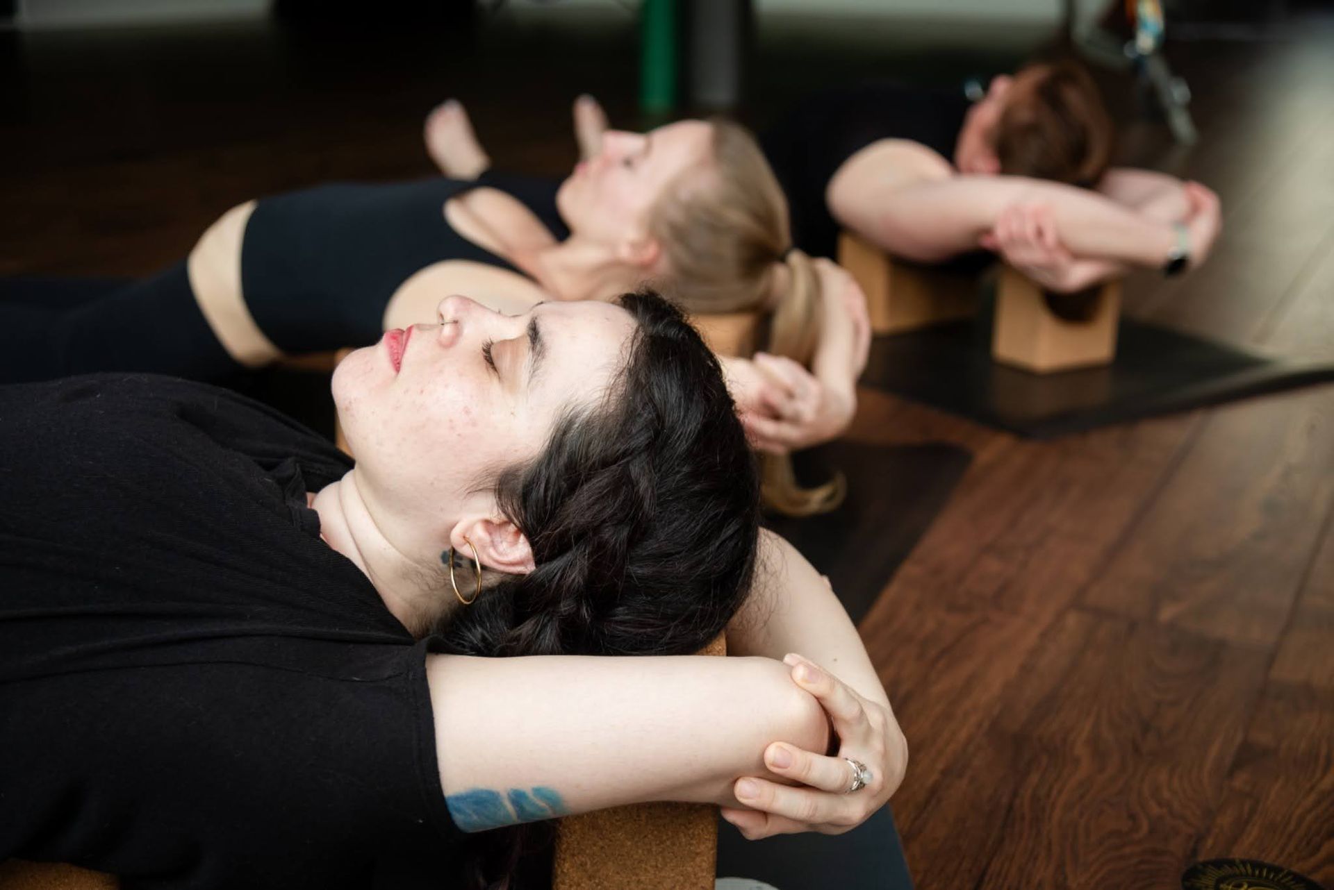 Instructor leading a group of women in a deep stretch yoga low lunge on mats at Uptown Yoga.