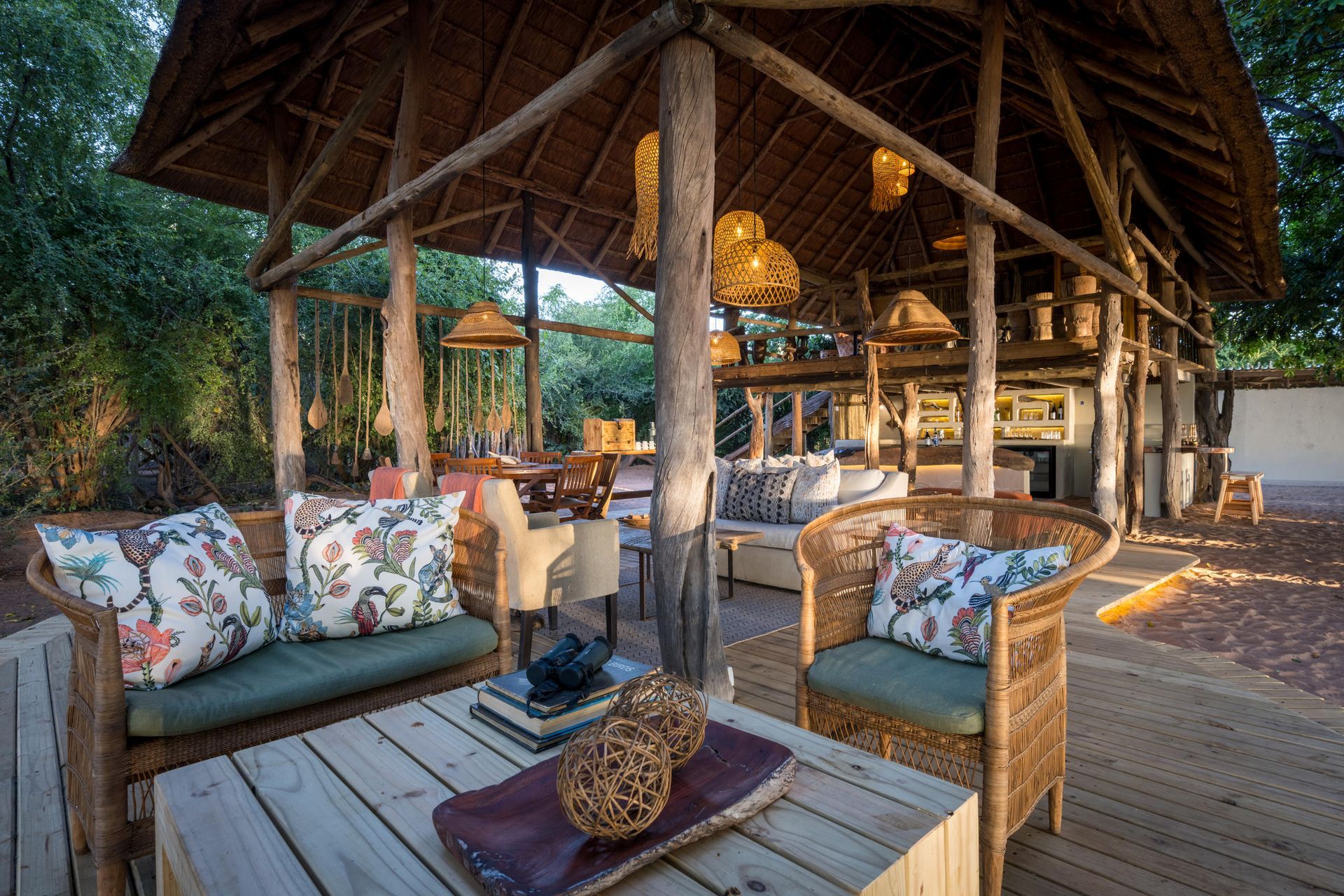 Outdoor wooden deck with comfortable chairs, pillows, and binoculars at an exclusive African safari camp.