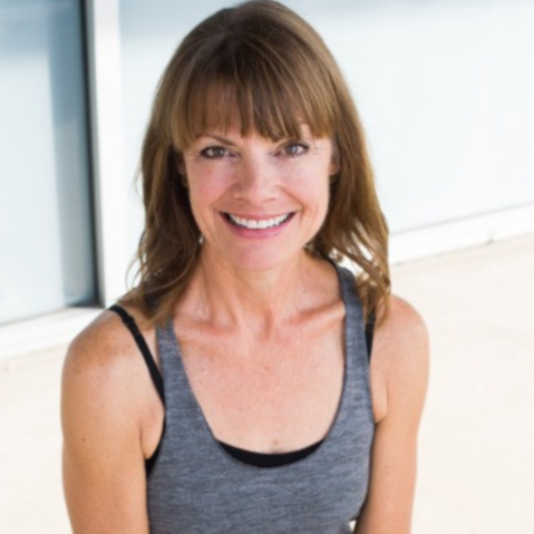 Headshot of Lisa Coyle, 500 E-RYT instructor and Ayurvedic Yoga Specialist at Uptown Yoga, wearing a grey athletic tank top outdoors.