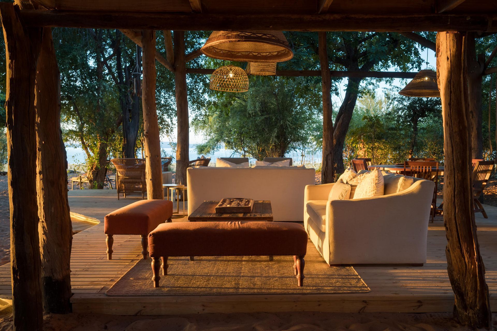 Cozy, open-air lounge area with plush seating inside a private safari camp looking out toward the water.