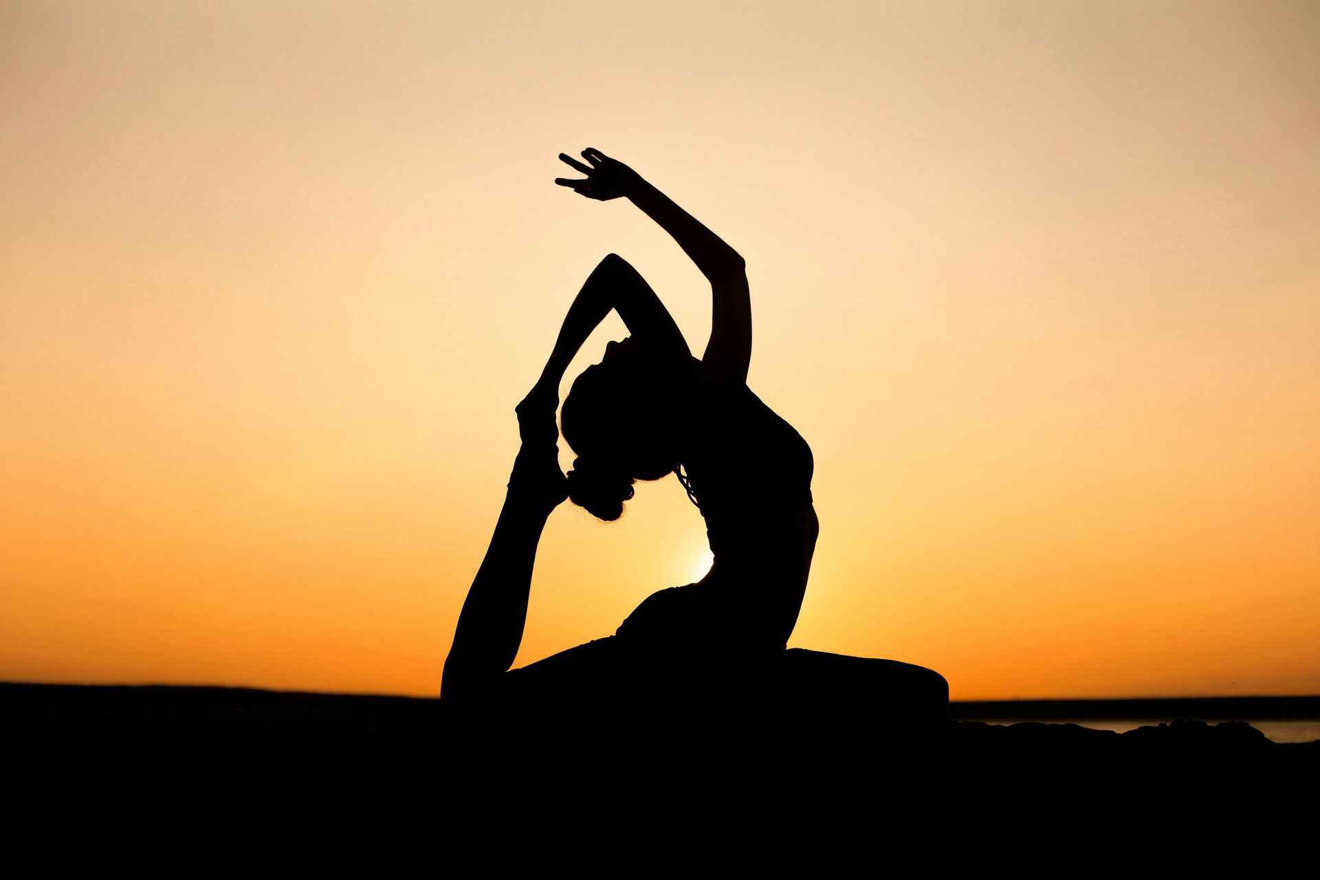 Silhouette of a person practicing yoga at sunset representing the peace of Seva Yoga and selfless service in Dallas.
