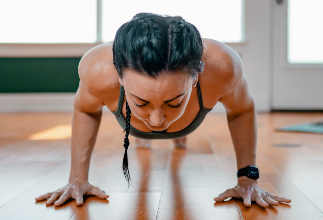 A woman holding a strong plank pose to build abdominal strength in a Strictly Core yoga and Pilates class.