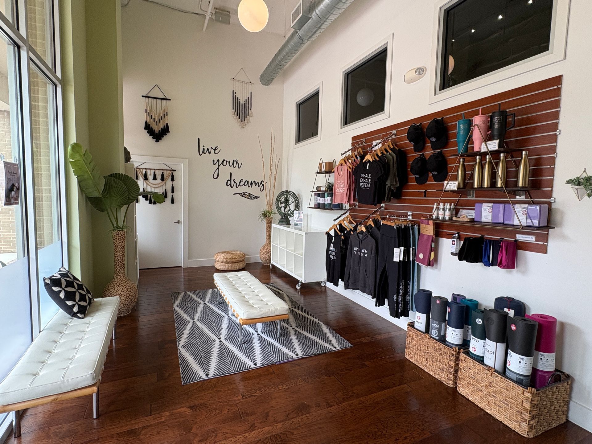 The welcoming lobby and retail boutique at Uptown Yoga Austin Ranch, displaying yoga apparel, Manduka mats, and accessories on hardwood floors.