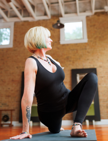 Uptown Yoga instructor Diana Tennant stretching in a grounded low lunge, leveraging over 20 years of experience to teach mind-body resilience and emotional balance.